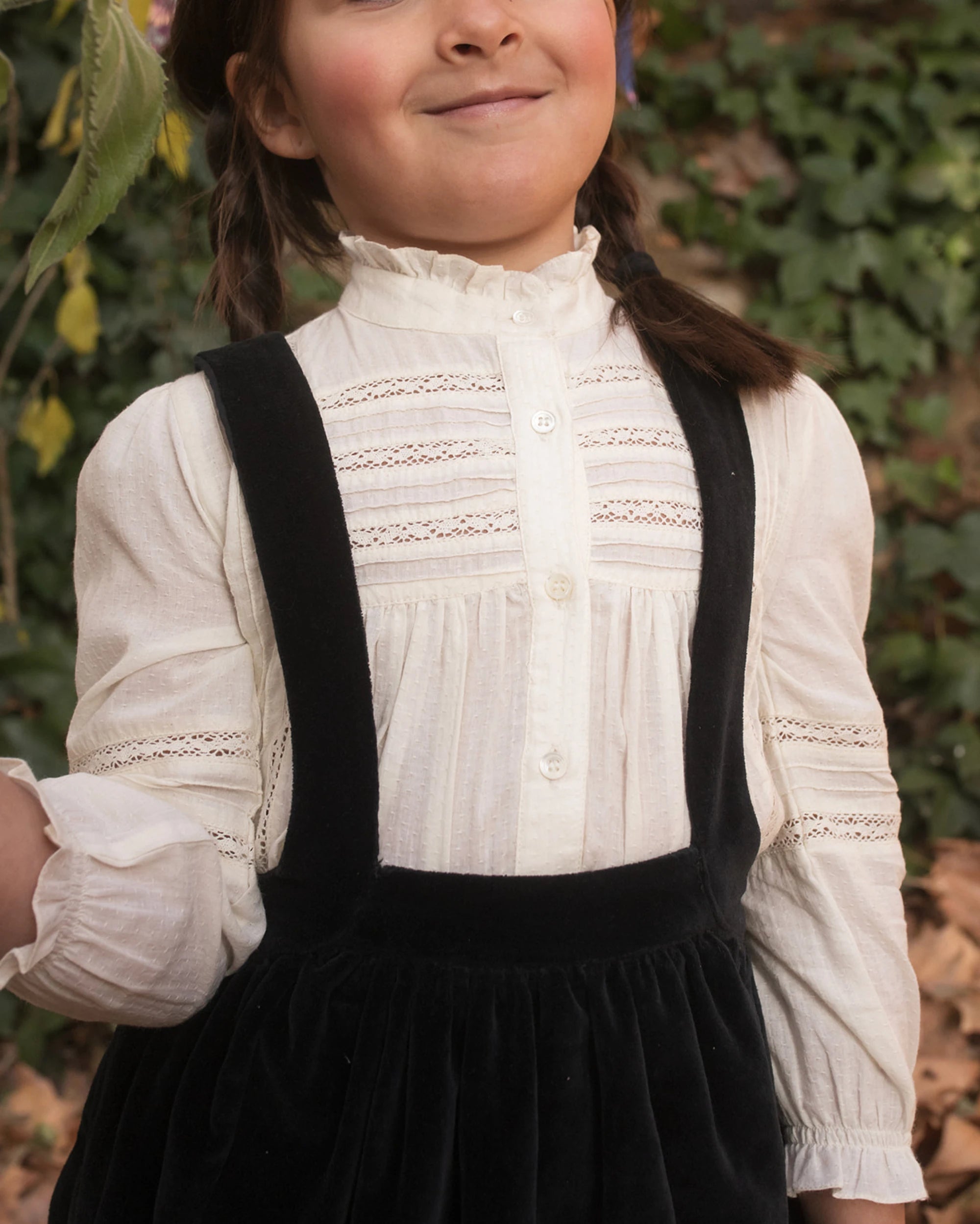 Early Sunday, Zoe Shirt in Ecru, made from Cotton Jeera Dobby Voile fabric, featuring frilled roundneck with detailed lace yoke, shown in a close up shot of model playing outdoors