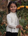 Early Sunday, Zoe Shirt in Ecru, made from Cotton Jeera Dobby Voile fabric, featuring frilled round neck with detailed lace yoke, shown in a front view of model wearing outdoors